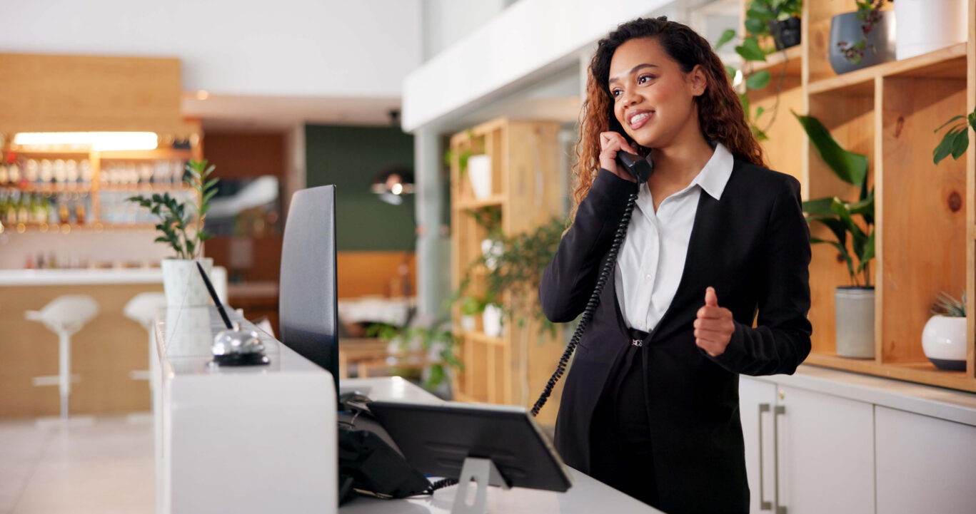 Hotel, reception and call of booking consultant with African woman, customer care and hospitality enquiry for villa. Staff, service and question at lobby desk with conversation, helping and support
