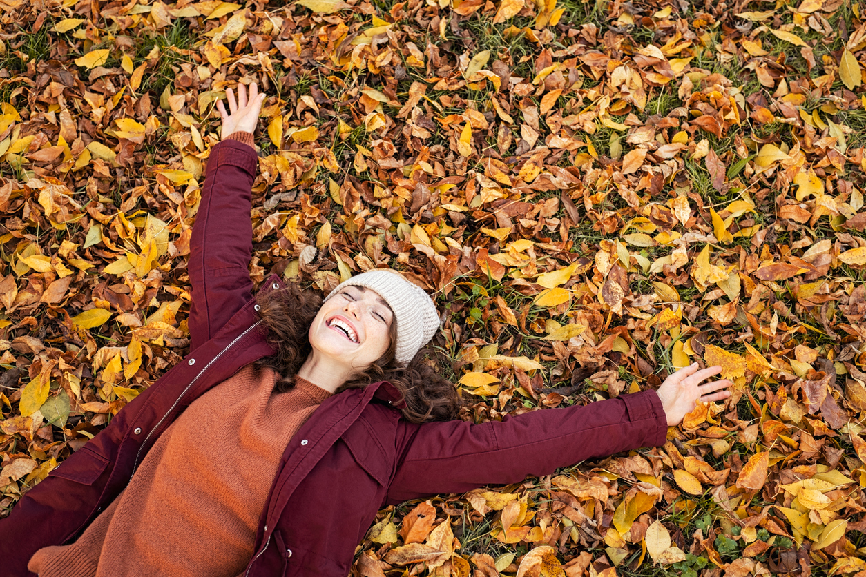 Top view of happy woman lying over yellow leaves