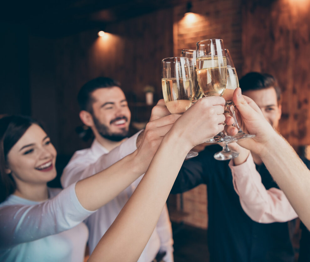 Cropped view raising up clinking wineglasses lovely attractive pretty cheerful positive guys ladies having fun greetings congrats festal birthday day feliz Navidad lights in industrial loft interior room