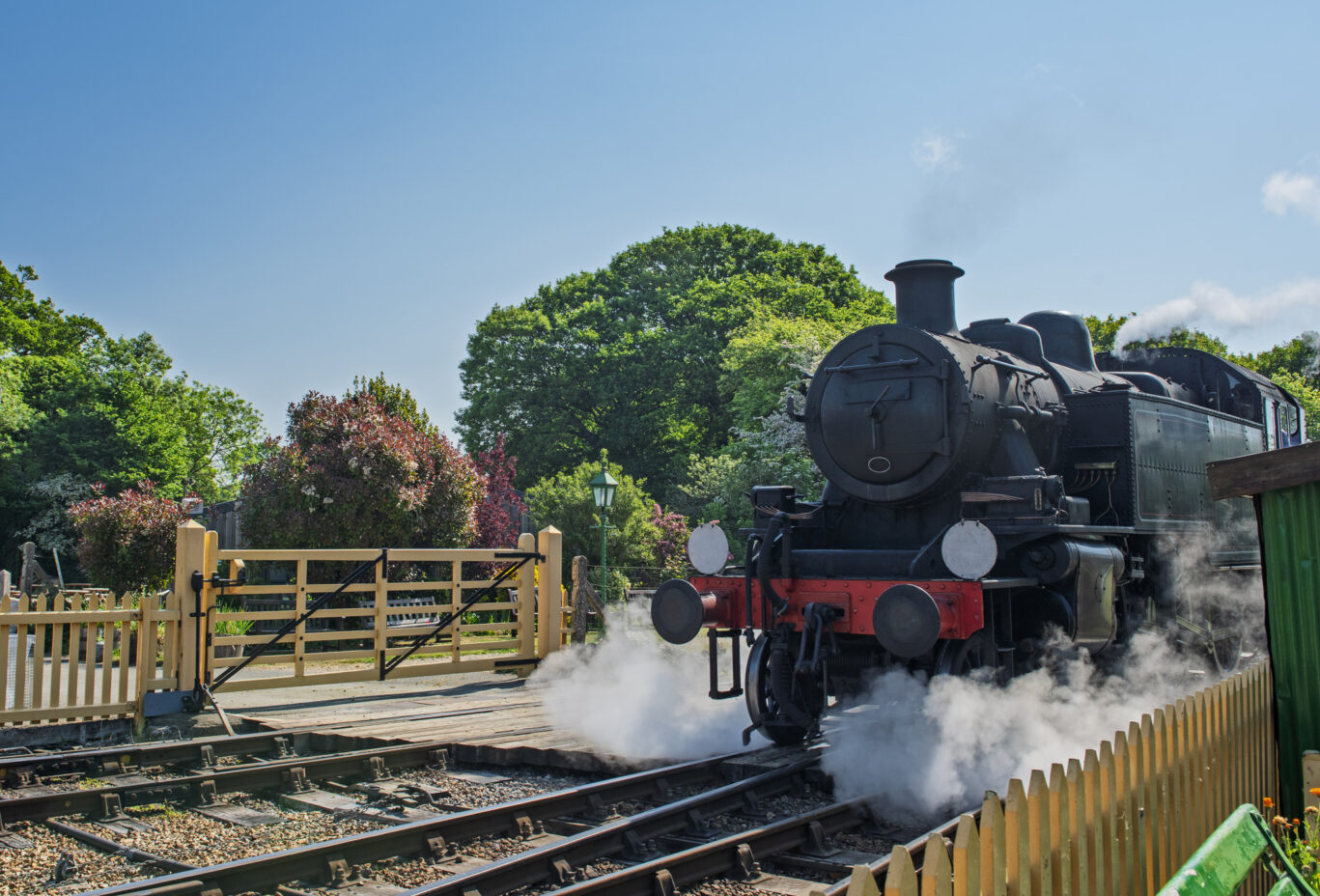 Old steam engine locomotive travelling over level crossing