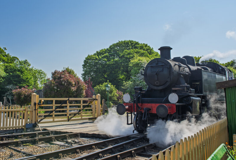 Old steam engine locomotive travelling over level crossing