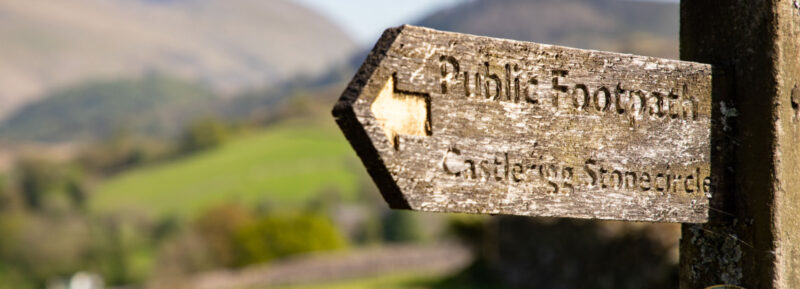 Public Footpath sign in front or rolling countryside