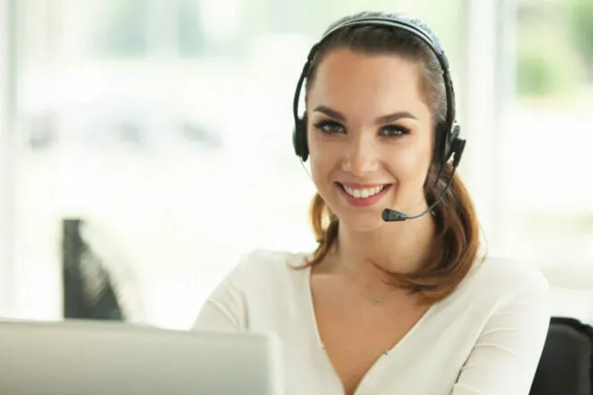 Female customer support operator with headset and smiling.