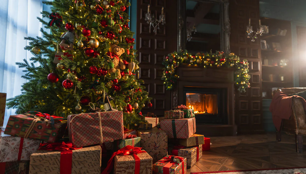 Classical Christmas decorated interior living room library with fireplace. Christmas tree with red golden ornament decorations. Modern classic style interior design apartment. Christmas eve at home.